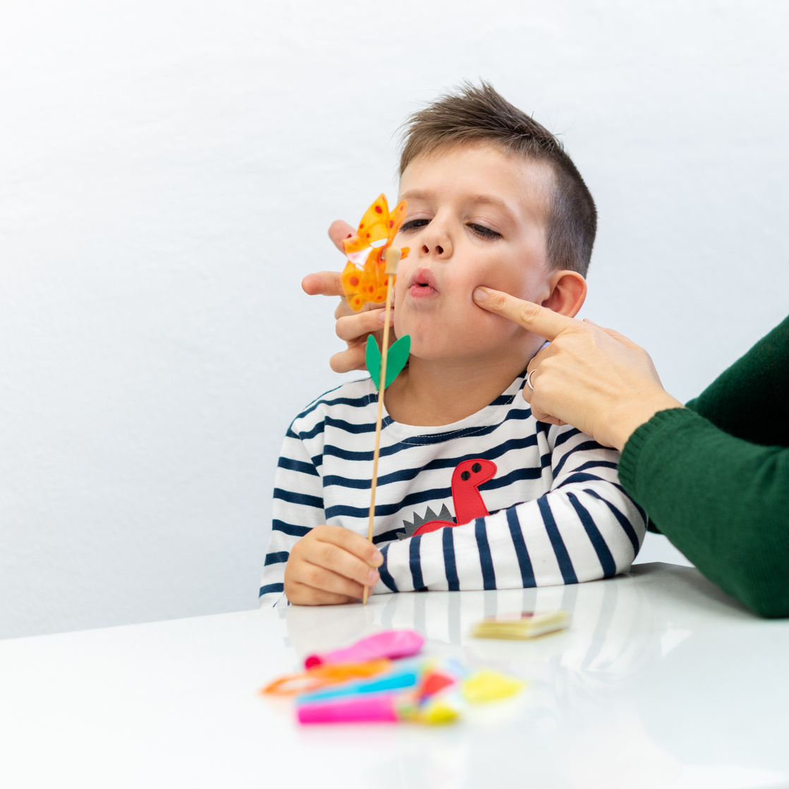 Young boy in speech therapy office. Preschooler exercising correct pronunciation with speech therapist.